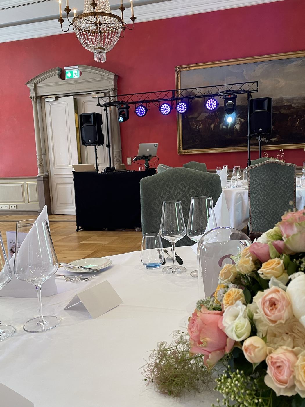 DJ-Setup in rotem Festsaal mit Blumendeko